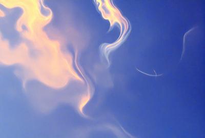 The primary subject of the image is a cloudy sky with a blue background. The sky is filled with smoke-like clouds, creating a dramatic and atmospheric scene. The visual style of the image is a combination of photo and digital art, as it captures the beauty of the cloudy sky while also showcasing the artistic elements of the smoke-like clouds. The colors and mood of the image are predominantly blue and moody, with the smoke-like clouds adding a sense of depth and intrigue to