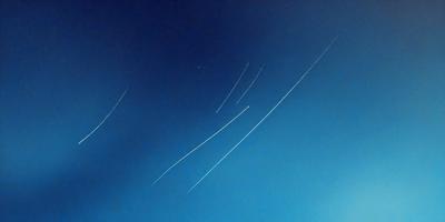 The primary subject of the image is a blue sky with a few streaks of light, possibly from a meteor shower or a firework display. The setting is a clear night sky, and the visual style appears to be a photo. The colors in the image are predominantly blue, with some white streaks, and the overall atmosphere is serene and peaceful.