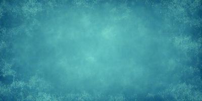 The primary subject of the image is a large, blue, textured surface. The setting is a dark, blue background, which creates a moody atmosphere. The visual style is a combination of a photo and a digital art, as it appears to be a close-up of a textured surface. The colors and mood of the image are predominantly dark and blue, giving it a somewhat mysterious and dramatic appearance.