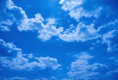 The primary subject of the image is a beautiful blue sky filled with clouds. The setting is a clear day with a cloudy sky, creating a serene atmosphere. The visual style is a natural, outdoor scene, with no indication of being a photo, digital art, illustration, drawing, pattern, texture, or clipart. The colors and mood are predominantly blue, with the clouds adding a touch of white and gray.