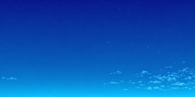 The primary subject of the image is the night sky, which is filled with stars. The setting is a clear, cloudless night, with the sky appearing dark and void of any clouds. The visual style of the image is a photo, capturing the beauty of the night sky. The colors and mood of the image are predominantly dark, with the stars providing a contrasting and serene atmosphere.