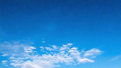 The primary subject of the image is a cloudy blue sky. The setting is a clear day with a blue sky, and the visual style is a natural, outdoor scene. The colors and mood of the image are predominantly blue and serene, creating a peaceful atmosphere.
