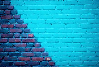 The primary subject of the image is a blue brick wall with a brick pattern. The setting is a brick wall, and the visual style is a photo. The dominant colors are blue and red, creating a vibrant and lively atmosphere.