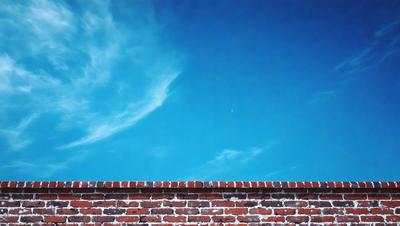 The primary subject of the image is a brick wall with a blue sky in the background. The setting is outdoors, and the visual style appears to be a photo. The colors in the image are predominantly blue, creating a calm and serene atmosphere.