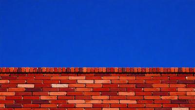 The primary subject of the image is a brick wall with a blue sky in the background. The setting is outdoors, and the visual style appears to be a photo. The colors in the image are predominantly blue and white, creating a calm and serene atmosphere.