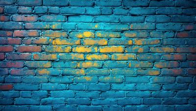 The primary subject of the image is a blue brick wall with yellow paint on it. The setting is a brick wall, and the visual style is a photo. The dominant colors are blue and yellow, creating a vibrant and lively atmosphere.