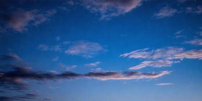 The primary subject of the image is the sky, which is filled with clouds. The setting is a clear blue sky, and the visual style is a photo. The colors in the image are predominantly blue and white, creating a calm and serene atmosphere.