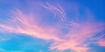 The primary subject of the image is a cloudy sky with a pinkish hue. The setting is a blue sky, and the visual style appears to be a photo. The colors and mood of the image are predominantly pink, creating a warm and serene atmosphere.