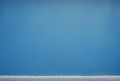The primary subject of the image is a blue wall. The setting is a room with a wooden floor. The visual style is a photo, and the dominant colors are blue and white. The overall atmosphere is calm and serene.