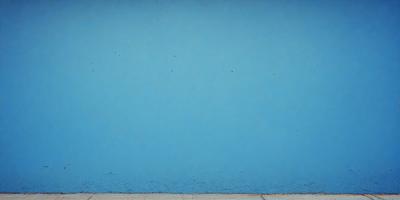 The primary subject of the image is a blue wall with a few white spots on it. The setting is an outdoor environment, possibly a beach or a poolside. The visual style is a photo, capturing the blue wall and its unique texture. The colors and mood of the image are predominantly blue, creating a calm and serene atmosphere.