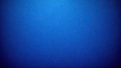 The primary subject of the image is a large, dark blue sky. The setting is a vast, open space with no visible landmarks or objects. The visual style is a natural, untouched environment. The colors and mood are predominantly dark and moody, with the blue sky serving as the main focal point.