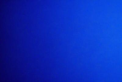 The primary subject of the image is a large, dark blue sky. The setting is a vast, open space with no visible landmarks or objects. The visual style is a natural, untouched environment. The colors and mood are predominantly dark and moody, with the blue sky serving as the main focal point.