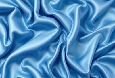 The primary subject of the image is a blue fabric, which appears to be a piece of silk. The setting is a blue background, and the visual style is a close-up of the fabric. The colors and mood of the image are predominantly blue, creating a calm and serene atmosphere.
