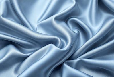 The primary subject of the image is a close-up of a blue fabric, possibly a piece of silk or satin. The setting is a room with a blue background, which adds to the overall atmosphere. The visual style is a close-up of the fabric, showcasing its texture and details. The colors and mood of the image are predominantly blue, creating a calm and serene atmosphere.