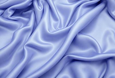 The primary subject of the image is a blue fabric, which appears to be a piece of silk. The setting is a close-up of the fabric, showcasing its texture and details. The visual style is a realistic representation of the fabric, with no indication of it being a photo, digital art, illustration, drawing, pattern, texture, or clipart. The dominant colors are blue and purple, creating a calm and serene atmosphere.