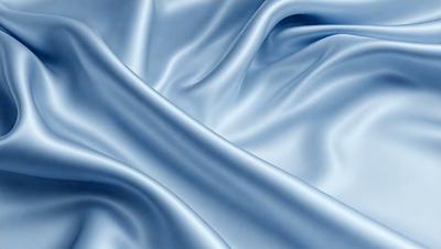 The primary subject of the image is a blue fabric, which appears to be a piece of silk. The setting is a close-up of the fabric, showcasing its texture and details. The visual style is a realistic representation of the fabric, with no indication of it being a photo, digital art, illustration, drawing, pattern, texture, or clipart. The colors and mood of the image are predominantly blue, creating a calm and serene atmosphere.