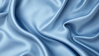 The primary subject of the image is a blue fabric, which appears to be a piece of silk. The setting is a close-up of the fabric, showcasing its texture and details. The visual style is a realistic representation of the fabric, with no indication of it being a photo, digital art, illustration, drawing, pattern, texture, or clipart. The colors and mood of the image are predominantly blue, creating a calm and serene atmosphere.