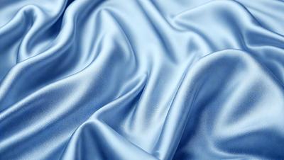 The primary subject of the image is a blue fabric, which appears to be a piece of silk. The setting is a close-up view of the fabric, showcasing its texture and details. The visual style is a realistic representation of the fabric, capturing its natural appearance. The colors and mood of the image are predominantly blue, creating a calm and serene atmosphere.