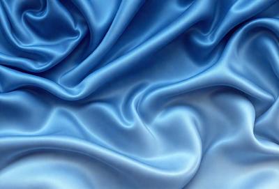 The primary subject of the image is a blue fabric, which appears to be a piece of silk. The setting is a blue background, which complements the blue fabric. The visual style is a close-up of the fabric, showcasing its texture and details. The colors and mood of the image are predominantly blue, creating a calm and serene atmosphere.