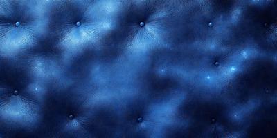 The primary subject of the image is a blue leather couch with a patterned design. The setting is a room with a blue background, and the visual style is a close-up of the couch. The colors and mood of the image are predominantly blue, creating a calm and relaxing atmosphere.