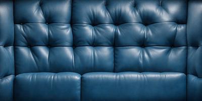 The primary subject of the image is a blue leather couch. The setting is a room with a blue background. The visual style is a photo, and the dominant colors are blue and black. The overall atmosphere is cozy and comfortable.