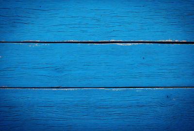 The primary subject of the image is a blue wooden surface, possibly a table or a wall. The setting is a room with a blue wooden floor, and the visual style is a close-up of the wooden surface. The colors and mood of the image are predominantly blue, creating a calm and serene atmosphere.