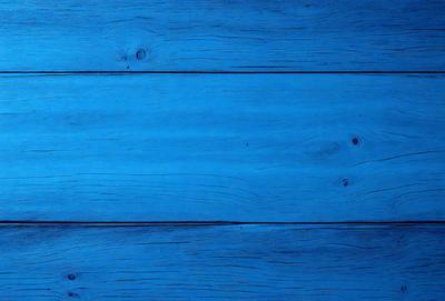 The primary subject of the image is a blue wooden wall. The setting is a room with a blue wooden floor. The visual style is a photo of a wooden wall. The dominant colors are blue and white, creating a calm and serene atmosphere.