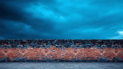 The primary subject of the image is a brick wall. The setting is a cloudy sky, and the visual style is a photo. The dominant colors are blue and gray, creating a moody atmosphere.