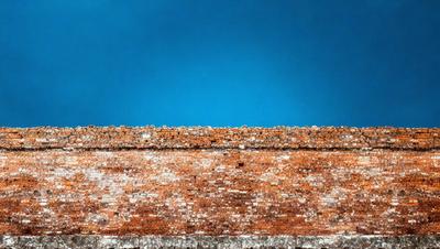 The primary subject of the image is a brick wall with a blue sky in the background. The setting is outdoors, and the visual style appears to be a photo. The colors in the image are predominantly blue and white, creating a calm and serene atmosphere.