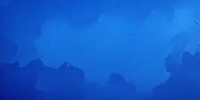 The primary subject of the image is a cloudy blue sky with a few birds flying in it. The setting is an open sky, and the visual style is a natural, outdoor scene. The colors and mood of the image are predominantly blue, with a hint of white clouds, creating a serene and peaceful atmosphere.