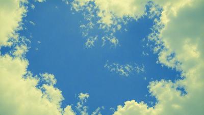 The primary subject of the image is a blue sky filled with clouds. The setting is a clear day with a cloudy sky, and the visual style is a natural, outdoor scene. The colors and mood of the image are predominantly blue and serene, creating a peaceful atmosphere.
