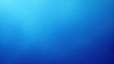 The primary subject of the image is a large, open, and vast body of blue water. The setting is a clear, cloudless sky, which provides a beautiful backdrop for the water. The visual style of the image is a photo, capturing the natural beauty of the ocean and the sky. The dominant colors in the image are blue and white, creating a serene and calming atmosphere.