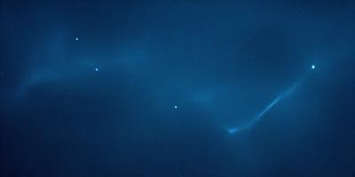 The primary subject of the image is a blue sky with a few stars visible. The setting is a night sky, and the visual style is a photo. The colors and mood of the image are predominantly blue, creating a serene and peaceful atmosphere.