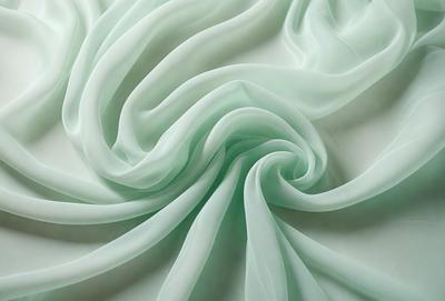 The primary subject of the image is a large, curled sheet of green fabric. The setting is a white background, which provides a clean and minimalist appearance. The visual style is a close-up of the fabric, showcasing its texture and details. The colors and mood of the image are predominantly green, giving it a calm and soothing atmosphere.
