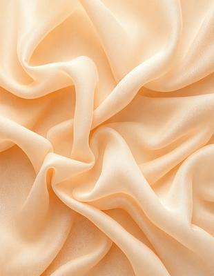 The primary subject of the image is a close-up of a piece of fabric, possibly a silk or satin material. The fabric appears to be a cream color, and it is wavy and flowing. The setting is a room with a wall, and the visual style is a close-up of the fabric. The colors and mood of the image are warm and inviting, with the cream-colored fabric creating a sense of luxury and elegance.