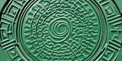The primary subject of the image is a green, circular, intricately designed pattern. The pattern is likely a decorative piece or a part of a larger design. The setting is a close-up of the circular pattern, showcasing its details. The visual style of the image is a combination of artistic and digital elements, as it appears to be a digital art or illustration. The colors and mood of the image are predominantly green, which gives it a calm and serene atmosphere.