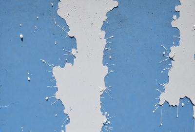 The primary subject of the image is a wall with white paint dripping down it. The setting is a blue wall, and the visual style appears to be a photo. The colors and mood of the image are predominantly white and blue, creating a clean and calming atmosphere.