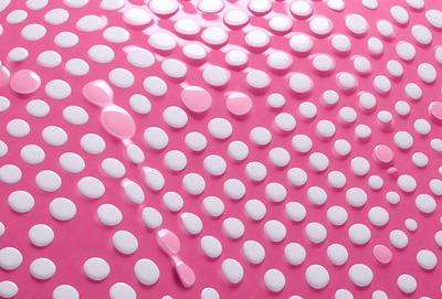 The primary subject of the image is a close-up of a pink surface with white dots. The setting appears to be a pink background, and the visual style is a patterned surface. The dominant colors are pink and white, creating a warm and inviting atmosphere.