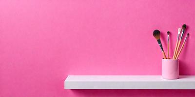 The primary subject of the image is a white shelf with a pink background. The setting is a room with a pink wall, and the visual style is a photo. The colors and mood of the image are predominantly pink, creating a warm and inviting atmosphere.