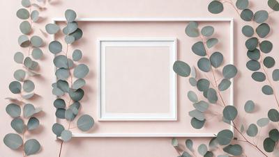 The primary subject of the image is a white square frame with a pink background. The setting is a wall with green leaves surrounding the frame. The visual style is a combination of a photo and a drawing, creating a unique and artistic appearance. The colors and mood of the image are predominantly pink and green, giving it a warm and inviting atmosphere.