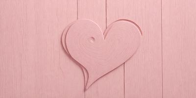 The primary subject of the image is a wooden heart-shaped cutout. The heart is placed on a pink background, which adds a warm and romantic touch to the scene. The visual style of the image is a combination of a photo and a drawing, creating a unique and artistic representation of the heart. The colors and mood of the image are predominantly pink, which evokes feelings of love and affection.