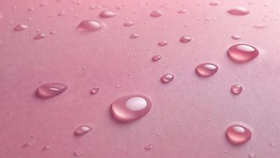 The primary subject of the image is a pink surface with water droplets on it. The setting is a pink background, and the visual style is a close-up of the pink surface with water droplets. The colors and mood of the image are predominantly pink, creating a warm and inviting atmosphere.