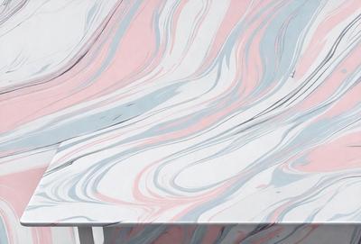 The primary subject of the image is a table with a marbled surface. The table is set against a backdrop of a colorful, swirling pattern that creates a visually striking and vibrant atmosphere. The visual style of the image is a combination of photo and digital art, as it captures the intricate details of the marbled surface and the swirling pattern. The colors and mood of the image are predominantly pink and blue, giving it a warm and inviting feel.