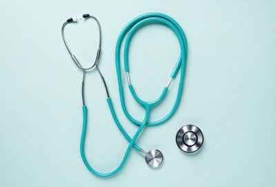 The primary subject of the image is a stethoscope, which is a medical device used by doctors and nurses to listen to a patient's heart and lung sounds. The stethoscope is placed on a green surface, which serves as the setting or background of the image. The visual style of the image is a close-up of the stethoscope, highlighting its details and making it the focal point of the picture. The colors in the image are predominantly green, which gives the scene a