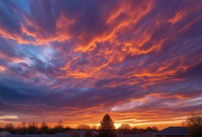 Primary subject: A beautiful sunset with a cloudy sky.

Setting/background: The sunset is taking place over a city, with houses and buildings visible in the background.

Visual style: The image is a photo of the sunset.

Colors and mood: The sunset is vibrant with warm colors, creating a serene and peaceful atmosphere.