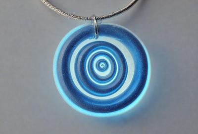 The primary subject of the image is a blue and white spiral design, which is likely a piece of art or a decorative item. The setting is a white background, which provides a clean and uncluttered environment for the spiral design. The visual style appears to be a combination of art and digital design, as the spiral design is displayed in a digital format. The colors and mood of the image are predominantly blue and white, creating a sense of calmness and elegance.