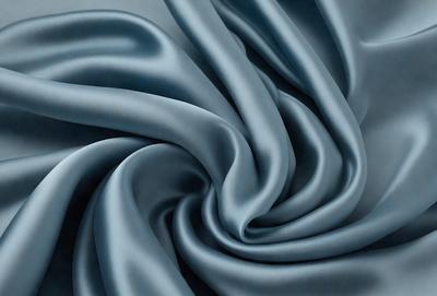 The primary subject of the image is a blue fabric, which is the main object, scene, or focus of the image. The setting or background is a gray surface, and the visual style is a photo. The dominant colors are blue and gray, creating a calm and soothing atmosphere.