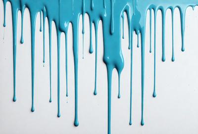 The primary subject of the image is a blue liquid dripping from a faucet onto a white surface. The setting is a kitchen, with the faucet being the main object in the scene. The visual style is a photo, capturing the dripping water in its natural motion. The dominant colors are blue and white, creating a calm and soothing atmosphere.