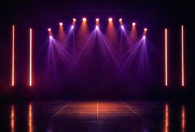 The primary subject of the image is a stage with a purple background and a row of lights shining on it. The stage appears to be empty, with no performers or objects visible. The setting is a theater or a similar venue, and the visual style is a realistic representation of the stage. The colors and mood of the image are predominantly purple, creating a dramatic and moody atmosphere.
