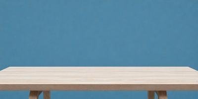 The primary subject of the image is a wooden table with a blue background. The table is positioned in front of a blue wall, creating a visually appealing contrast. The visual style of the image is a photo, capturing the details of the wooden table and the blue wall. The colors and mood of the image are predominantly blue, giving it a calm and serene atmosphere.